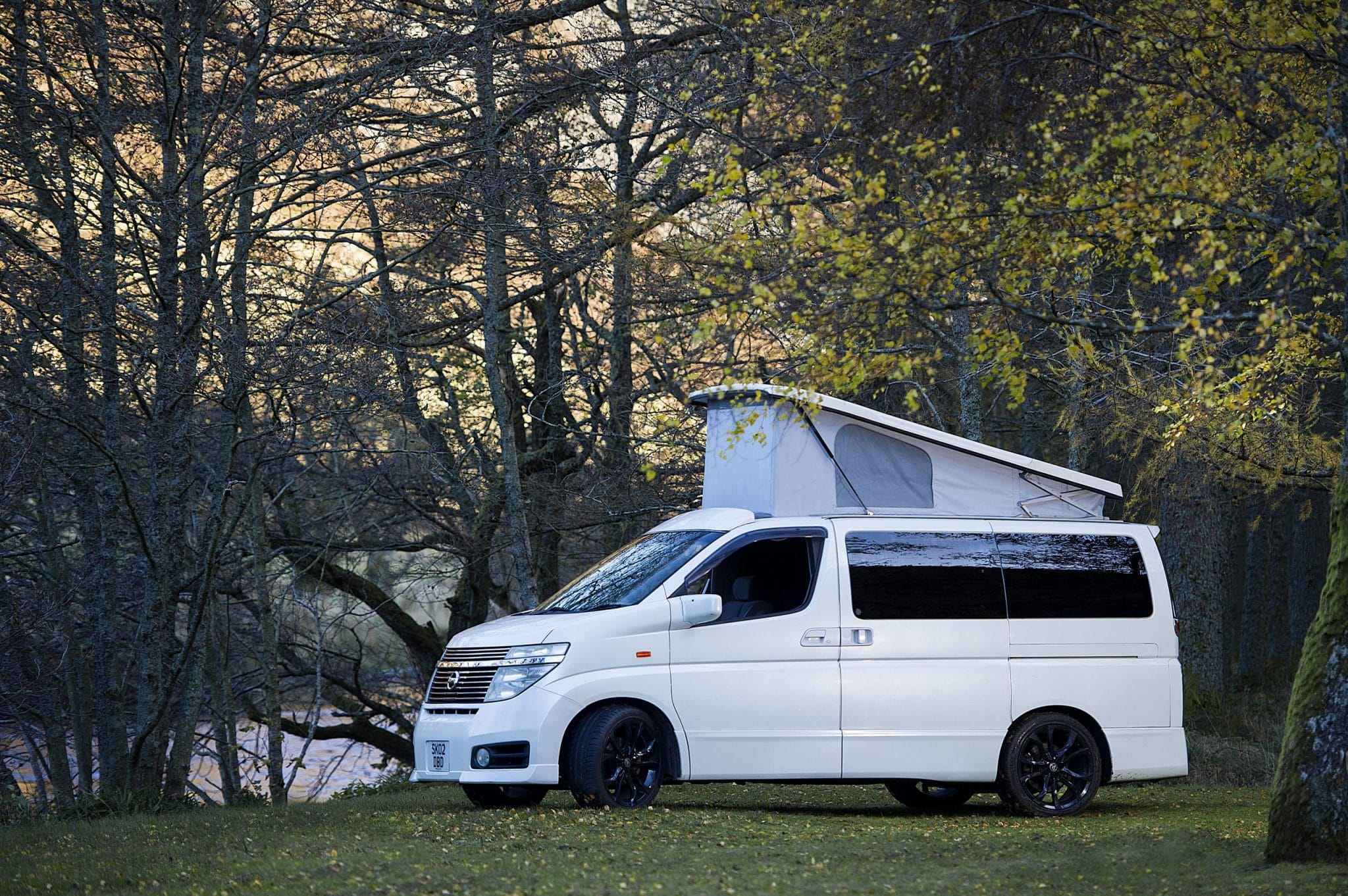 White nissan elgrand veolcity campervan with rooftop box in country side
