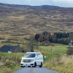 White nissan elgrand campervan parked in scenic countryside landscape with scottish hills behind
