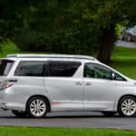 Offside view of silver Toyota Alphard Connect II Campervan in garden park with roof down