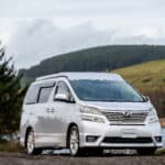 Toyota Alphard Connect II Campervan in mountain area with roof up next to loch roof down