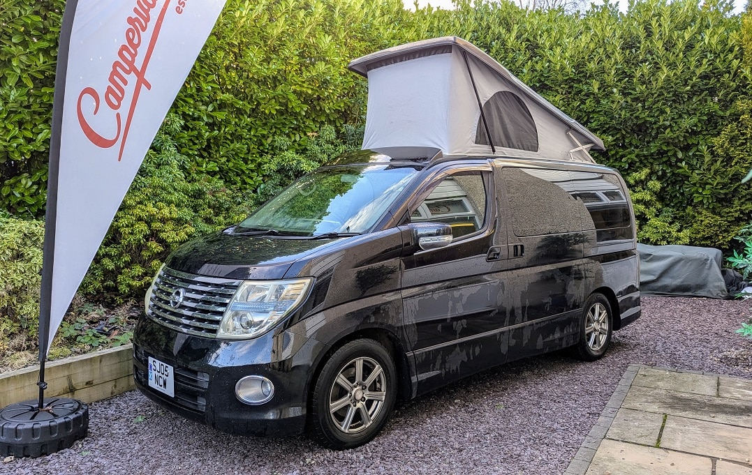 Black Nissan Elgrand Velocity with roof up forecourt with flag