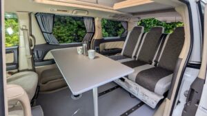 Toyota Alphard Hybrid Eco Explorer ZME white living area with table and bed up from the side